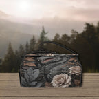 Floral and dragon design handbag on a wooden surface with a forest background