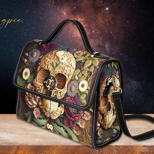 Decorative handbag with skull and floral design on a wooden surface with a starry night sky background.