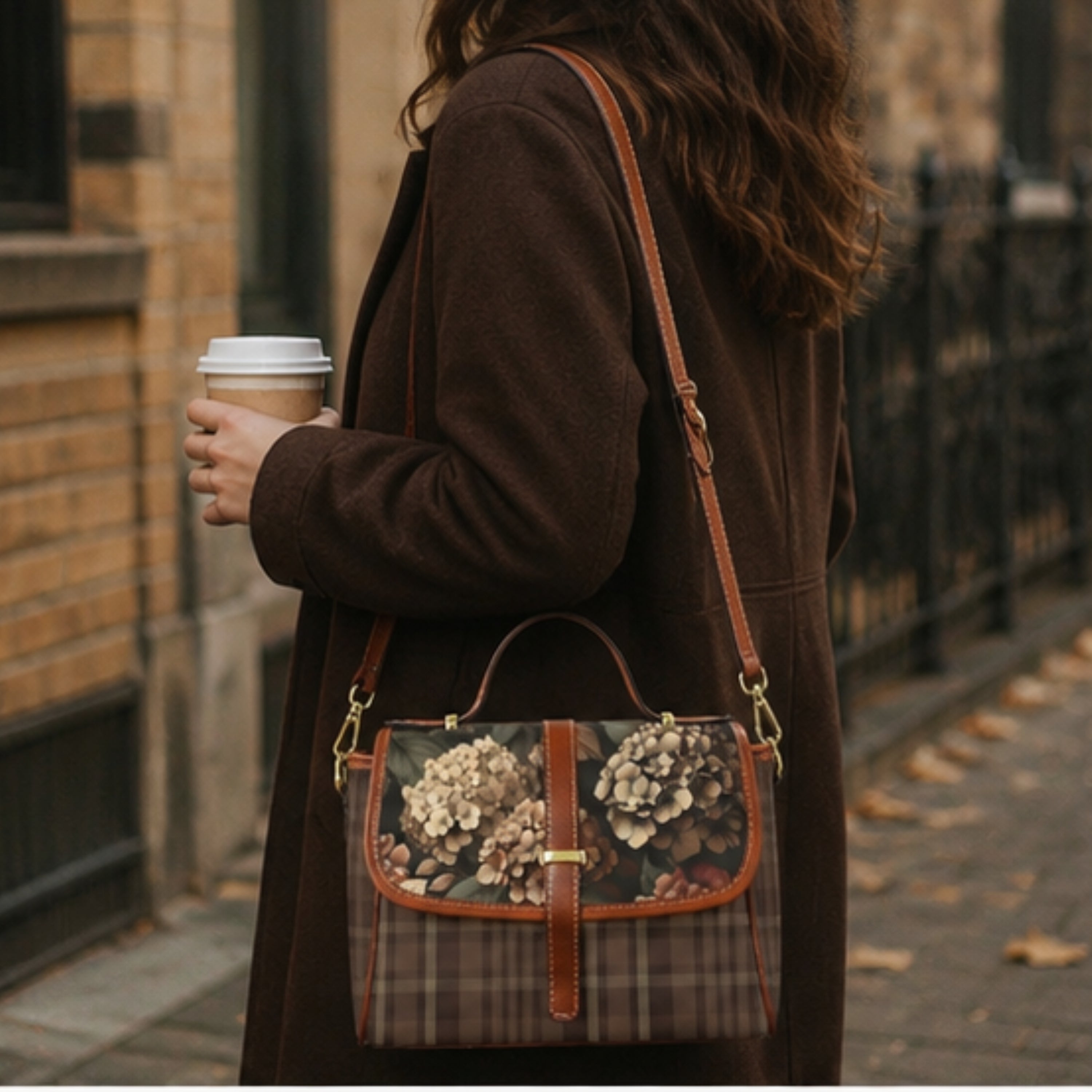 Person holding a floral-patterned handbag and a coffee cup on a street.