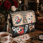 Handbag with playing card design on a table with tea and keys