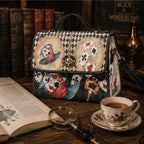 Handbag with playing card design on a wooden table with a book and tea cup in the background