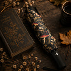 Decorative umbrella with floral pattern on a wooden surface with book and dried flowers.