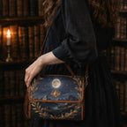 Person holding a decorative bag with a moon and mountain design in a library setting