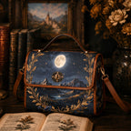 Handbag with night sky and mountain design on a wooden surface with books and flowers.
