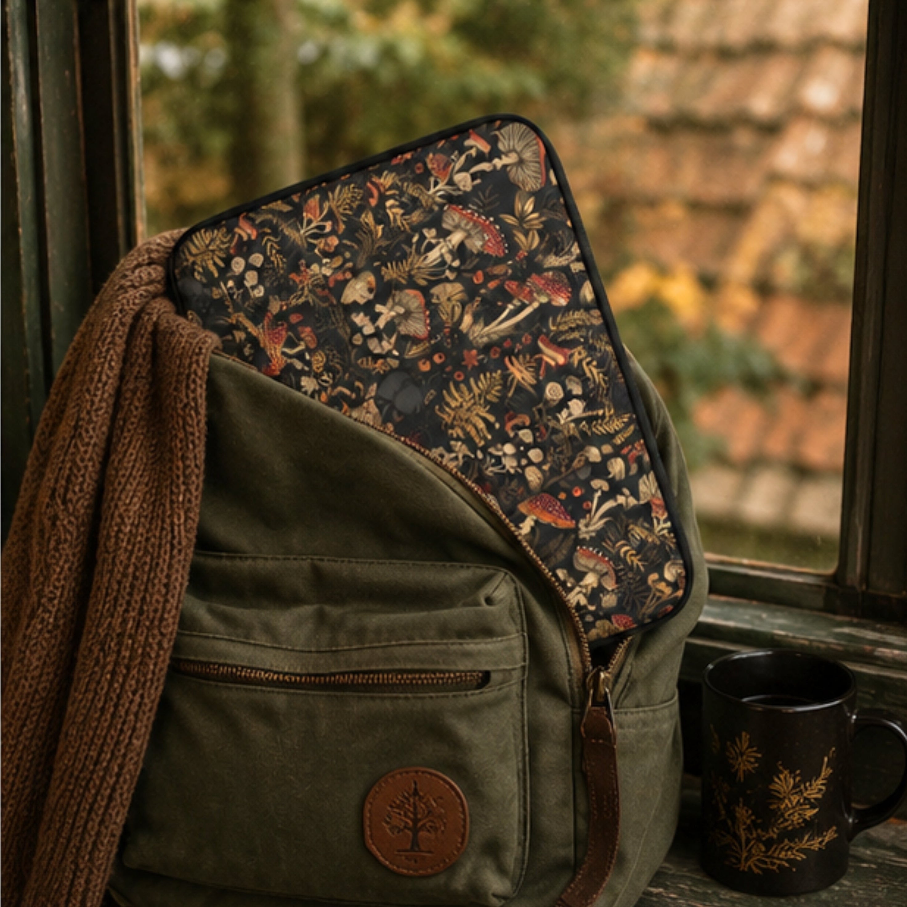 Floral-patterned bag with a brown scarf and mug by a window