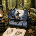 A witch-themed handbag with a printed illustration of a witch riding a broomstick under a full moon, styled in a forest setting with an open book, a candle lantern, and a mug.