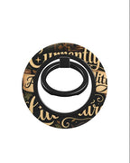 A circular black ring holder featuring a decorative gold and black script pattern, shown against a plain white background.