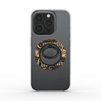 A dark gray phone case with a clear bumper edge, featuring a circular gold and black decorative graphic with gothic lettering and a black ring stand in the center.
