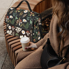 Person sitting on a bench with a floral-patterned handbag and a coffee cup.