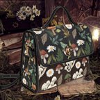 Handbag with nature-themed design featuring mushrooms and flowers on a dark background.
