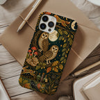 A phone case with a detailed woodland owl illustration pattern, shown in a styled flat-lay on a rustic wooden desk surrounded by notebooks, a pen, and a cup of coffee.