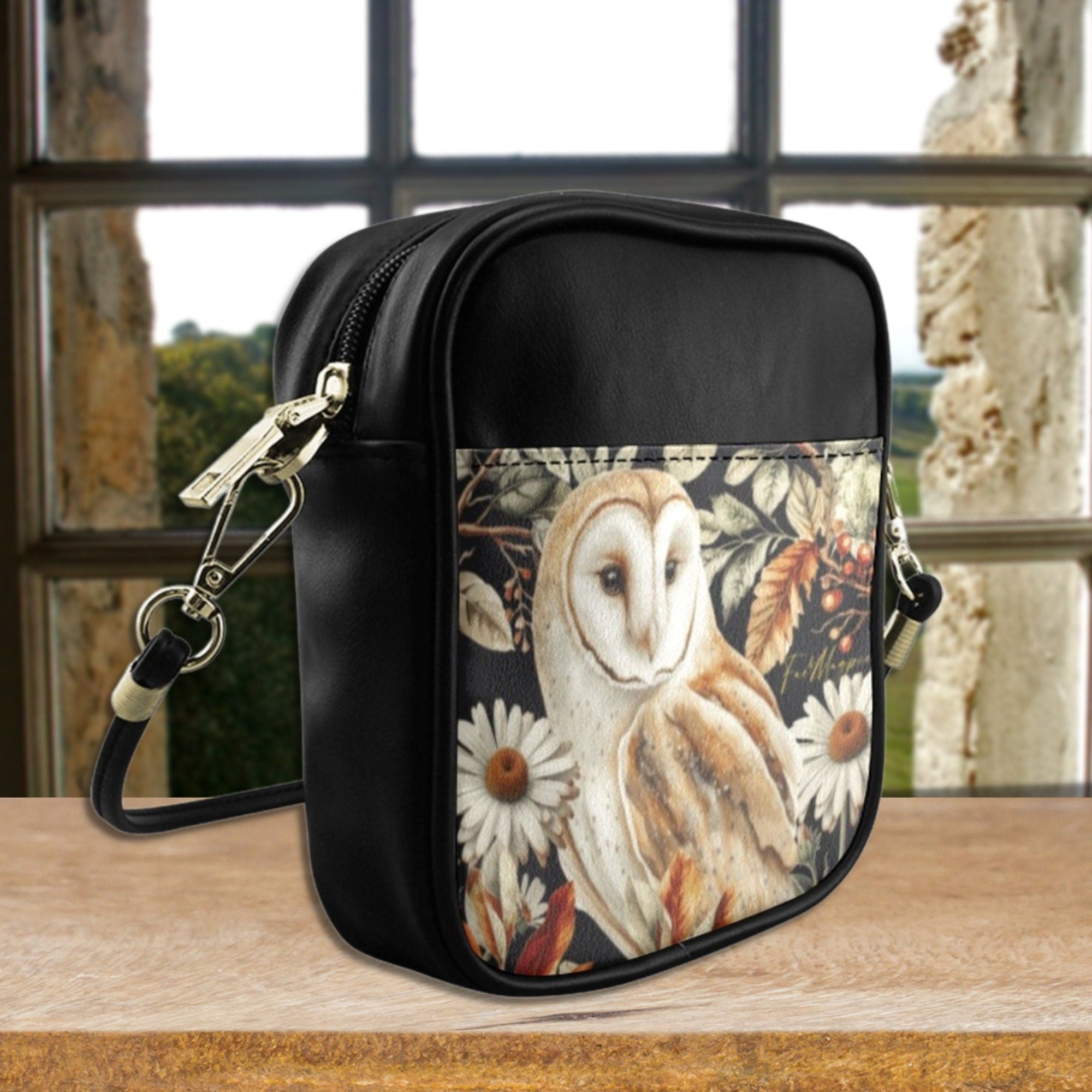 Black leather bag with owl design on a wooden surface