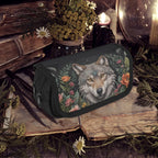 Floral-patterned pouch with a wolf design on a rustic background with books and plants.